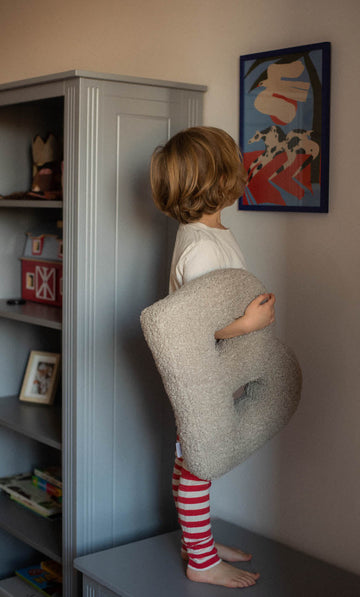 kid with boucle letter cushion b by Bettys home standing on table