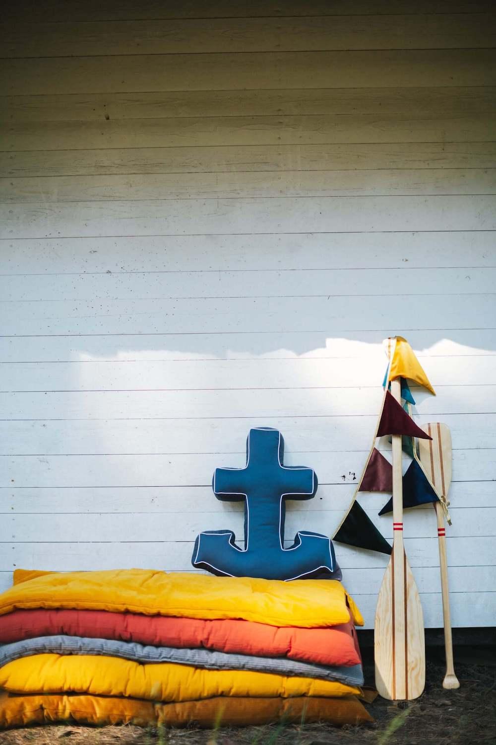 navy blue anchor cushion from bettys home stands on a lakeside beach 
