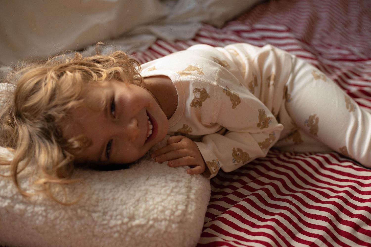 Qute little boy lying on teddy letter cushion by bettys home on his bed