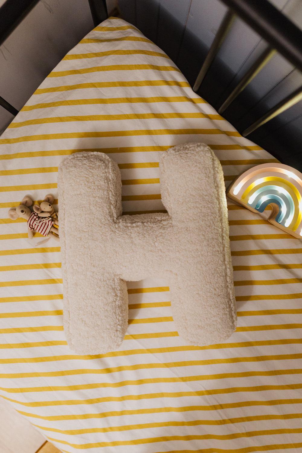 Boucle letter cushion H teddy pillow by bettys home lying in kids bed next to maileg mouse and little lights rainbow lamp