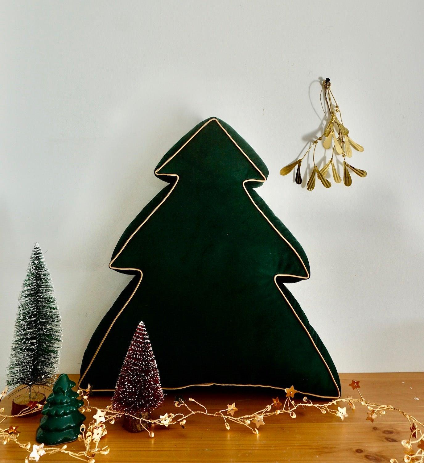 Christmas Tree Cushion Green by Bettys Home next to christmas decorations on table 
