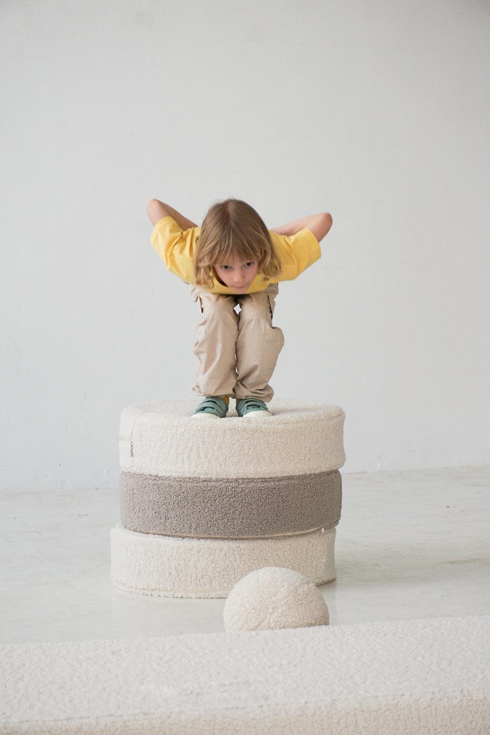 boy jumping of large boucle poufs by bettys home 2