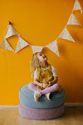 child sitting on two corduroy poufs by Bettys home