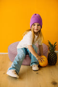 Little girl sitting on large corduroy floor pouf lavender by Bettys home 