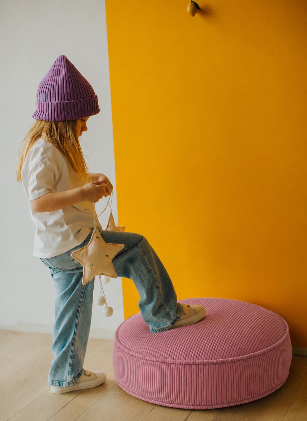small girl standing with one leg on large corduroy floor pouf pink by Bettys home 