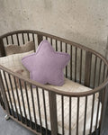 Lavender corduroy star cushion styled in oval wooden crib against concrete wall by Bettys Home