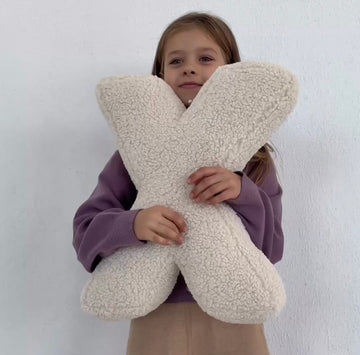 Little girl holding boucle letter cushion X in creme by bettys home
