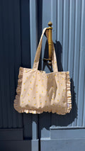 cotton tote bag with ruffle by Bettys home and lemon print hanging on blue doors